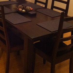 May include: A dark brown wooden dining table with six chairs. The table has a dark brown finish and is surrounded by six chairs with a dark brown finish. The chairs have a slatted back and are made of wood.