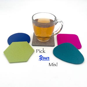 May include: A clear glass teacup filled with tea sits on a gray coaster, surrounded by colorful felt coasters in blue, green, teal, and pink. The text "Pick Your Mix!" is displayed in the image.