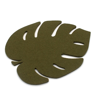 May include: A green felt coaster shaped like a monstera leaf. The coaster is a simple design with a cut-out shape.