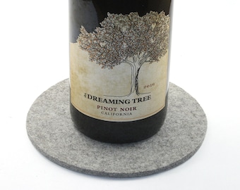 May include: A grey felt coaster with a bottle of "The Dreaming Tree" Pinot Noir wine on top. The bottle label features a drawing of a tree and the year 2010.