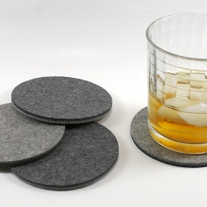 May include: Four gray felt coasters with a glass of iced tea on one of the coasters.
