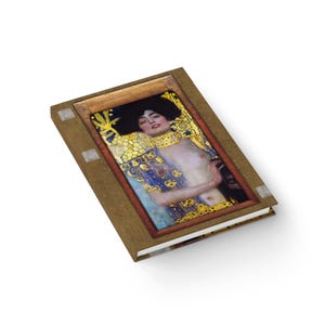 May include: A brown leather-bound journal with a gold frame around a painting of a woman with long dark hair and a gold necklace. The painting is of a woman with a blue and gold robe.