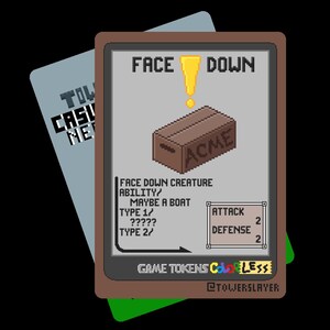 May include: A pixelated game card with the words "FACE DOWN" above a brown box labeled "ACME." The card features game stats and text, including "ATTACK 2" and "DEFENSE 2." A second card is partially visible in the background.