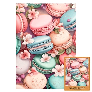 Può includere: Un'illustrazione colorata di macarons nei toni del rosa, blu e pesca, intervallati da delicati fiori rosa e foglie verdi. L'immagine è un primo piano, che mostra i dettagli dei pasticcini. Un puzzle in legno più piccolo con lo stesso design si trova nell'angolo in basso a destra.