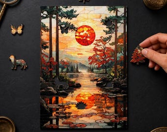 May include: A rectangular wooden jigsaw puzzle featuring a stained-glass style landscape of a lake at sunset with tall trees, red foliage, and lily pads. The puzzle includes unique shaped pieces like a butterfly, a fox, and a tree.