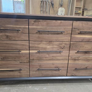 6foot 9 drawer walnut faced modern dresser in black with solid walnut top on steel legs.