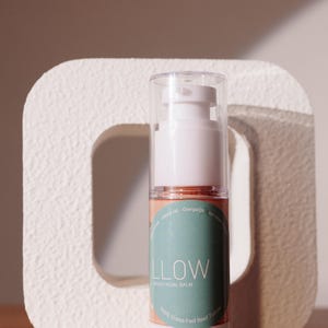 Könnte beinhalten: Eine weiße Flasche mit einer Pumpspender für einen getönten Gesichtsbalsam. Die Flasche hat ein grünes Etikett mit dem Text "LLOW TINTED FACIAL BALM" und "100% Grass-Fed Beef Tallow".