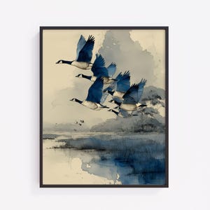 May include: Watercolor print of a flock of geese in flight, with blue and white wings against a muted, watercolor background. The artwork depicts a marshy landscape with a dark frame.