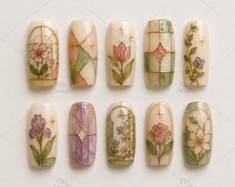 May include: A collection of ten artificial nails with floral designs. Each nail features a different hand-painted design, including flowers, geometric patterns, and stained-glass window motifs. The nails are in various shades of beige, pink, green, and purple.