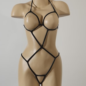May include: A black lingerie set with a geometric design. The set features a halter top with a criss-cross pattern and a matching bottom.