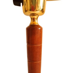 May include: A close-up of a vintage lamp. The lamp features a wooden base with a series of stacked cylindrical sections. The lamp's upper portion has a gold-colored metal fixture and a yellow lampshade. A black switch is visible.