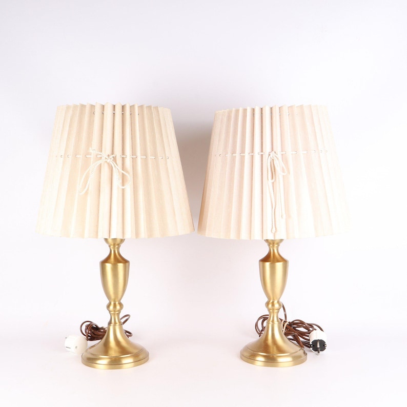 Op de afbeelding: Een witte keramische mok met een zwart handvat en de tekst "But First, Coffee" in een vetgedrukte, zwarte letter. De mok staat op een houten oppervlak. De mok is ongeveer 10 cm hoog.
