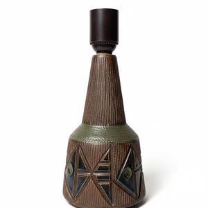 Könnte beinhalten: Ein brauner Keramik-Lampensockel mit strukturierter Oberfläche und geometrischen Designs in Blau und Grün. Die Lampe hat oben eine dunkelbraune Lampenfassung und ein grünes Band in der Mitte.