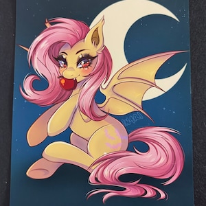 May include: Illustration of a pony with bat wings, a crescent moon, and a dark blue background. The pony has yellow fur, pink hair, and is holding a red apple. The image has a cartoon style.