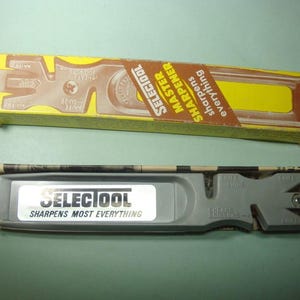 May include: A gray Selectool knife sharpener with the text "SHARPENS MOST EVERYTHING" and a yellow and brown box that reads "MASTER SHARPENER". The box has a diagram of a knife guide.