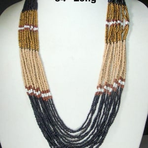 May include: A multi-strand beaded necklace, approximately 34 inches long. The necklace features black, tan, gold, white, and brown beads. The text "34" Long" is visible in the image.