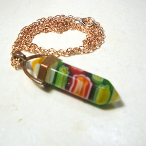 May include: A gold chain necklace with a colorful glass pendant. The pendant is shaped like a point and has a variety of colors, including green, red, yellow, and white.