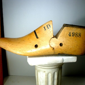 May include: A wooden shoe last with a hinged design. The last is marked with the numbers "1D" and "4988".