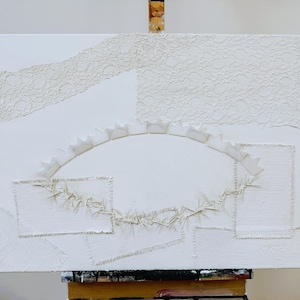 May include: White abstract art piece on canvas. The artwork features textured elements, including lace-like patterns and stitched rectangular shapes. A semi-circular shape with a scalloped edge is a prominent design element.