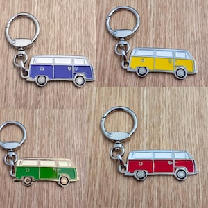 Puede incluir: Cuatro llaveros con miniaturas de furgonetas camper de colores. Cada furgoneta tiene un llavero plateado y está pintada de un color diferente: azul, amarillo, verde y rojo. Las furgonetas tienen techos blancos y ruedas plateadas. Las furgonetas miden unos 5 cm.