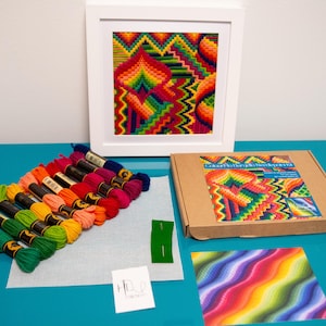 May include: A colorful embroidery kit with a framed geometric design in a white frame. The kit includes spools of thread in various colors, a piece of fabric, and a cardboard box with a colorful design on the front.