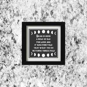 May include: Black framed art print with a white border. The black background features white text that reads "Bear in mind a rule of old for long ago it was foretold that what you do returns three fold." The design includes moon phases.