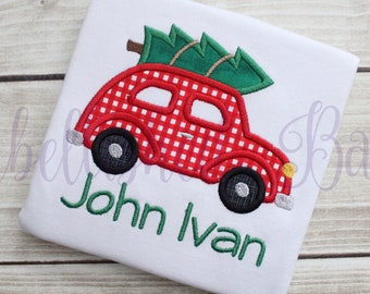 May include: A red and white gingham car with a green Christmas tree on top. The car has black wheels and a yellow headlight. The name "John Ivan" is embroidered in green below the car.