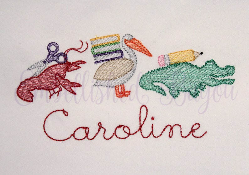 Puede incluir: Dise&ntilde;o bordado con un langostino rojo sosteniendo tijeras, un pel&iacute;cano cargando una pila de libros, un cocodrilo verde con un l&aacute;piz amarillo en la espalda y el nombre "Caroline" en hilo rojo.