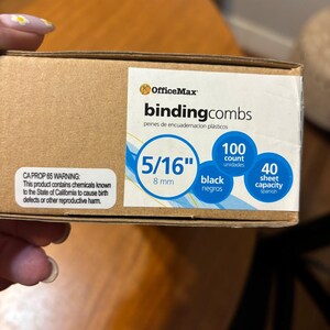 May include: A cardboard box of OfficeMax binding combs. The label indicates 5/16 inch (8 mm) black combs with a 100-count and a 40-sheet capacity. The box also includes a California Proposition 65 warning.