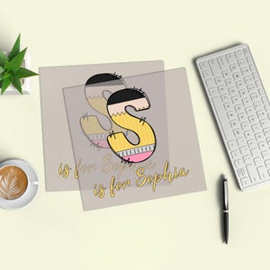 May include: A pencil-themed letter "S" design with the text "is for Sophia" in a handwritten style. The letter is yellow, black, and pink, with a pencil-like appearance. The design is on a light gray background.