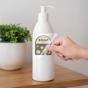 May include: A clear bottle with a pump dispenser and a sticker that says "handmade soap organic" with a floral design.