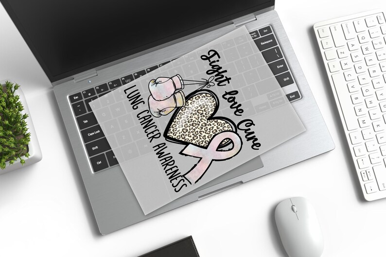 a laptop with a printed design on the screen, which includes a heart and a pink ribbon symbolizing lung cancer awareness.