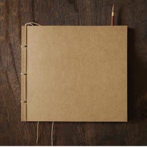 Könnte beinhalten: Ein braunes, rechteckiges Notizbuch mit schlichtem Design. Das Notizbuch ist mit einer Schnur gebunden und hat einen rustikalen Look.