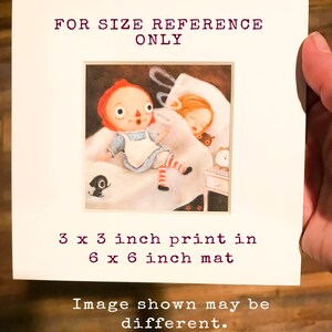May include: A 3x3 inch print of a red-haired doll sitting on a bed with a girl sleeping next to her. The print is matted in a 6x6 inch mat. The image shown may be different.
