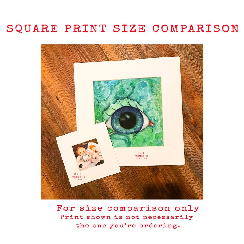 May include: Two square prints of artwork, one with a blue eye and green background, the other with a cartoon image. The larger print is matted to 12x12 inches, the smaller print is matted to 6x6 inches. "For size comparison only. Print shown is not necessarily the one you're ordering."
