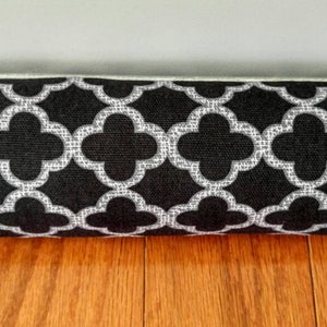 May include: A black and white doorstop with a geometric pattern. The doorstop is made of fabric and is filled with a soft material.