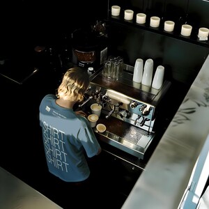 Cafe t-shirt barista mockup in a realistic cafe scene with editable PSD layers, perfect for branding design.