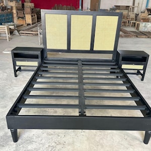 May include: A black bed frame with a headboard featuring three rectangular woven panels. Two matching bedside tables with woven drawer fronts flank the bed. The bed frame has a slatted base and is supported by four rounded legs.