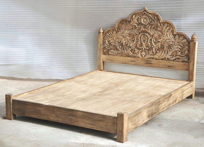May include: A light brown wooden bed frame featuring a tall headboard with intricate, hand-carved floral and leaf patterns. The bed includes a flat platform base and four sturdy corner posts, showcasing a natural wood grain finish throughout.