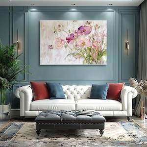 May include: A white sofa with red and blue pillows in a room with a large painting of pink flowers on a blue wall.