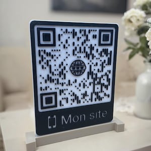 Peut inclure: Panneau de code QR noir et blanc avec le texte "Mon site" et une icône de téléphone. Le panneau a un fond blanc avec un motif de code QR noir et une icône de globe au centre. Il est affiché sur un support beige.