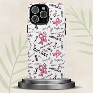 May include: A white phone case with a repeating pattern of pink ribbons, hearts, and words like "Survivor," "Warrior," and "Hope." The case is designed to fit a smartphone and is displayed on a small, dark gray pedestal.