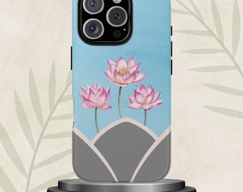 May include: A light blue phone case featuring a watercolor design of three pink lotus flowers with yellow centers. The design includes a gray geometric shape at the bottom. The phone case is displayed on a gray stand.