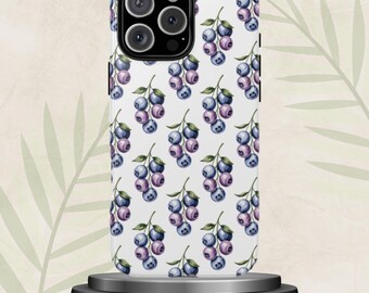 May include: A white phone case featuring a repeating pattern of watercolor blueberries in shades of blue and purple. The phone case is displayed on a small, round, silver stand against a neutral background with a leaf design.