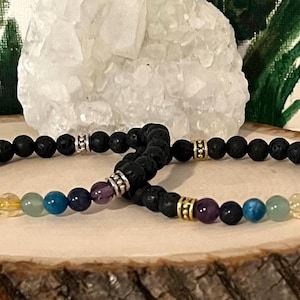 May include: Two black lava stone bracelets with seven chakra coloured beads. The beads are red, orange, yellow, green, blue, indigo, and violet.