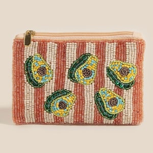 May include: A beaded coin purse with a peach and white striped pattern. The purse is decorated with five avocado designs, each with green, yellow, and blue beadwork. It has a gold zip closure.