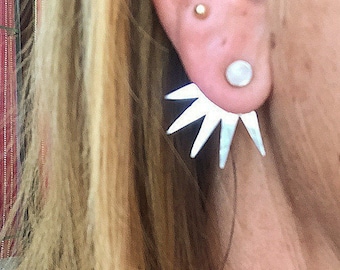 May include: Silver starburst earrings with a white pearl stud in the lobe.