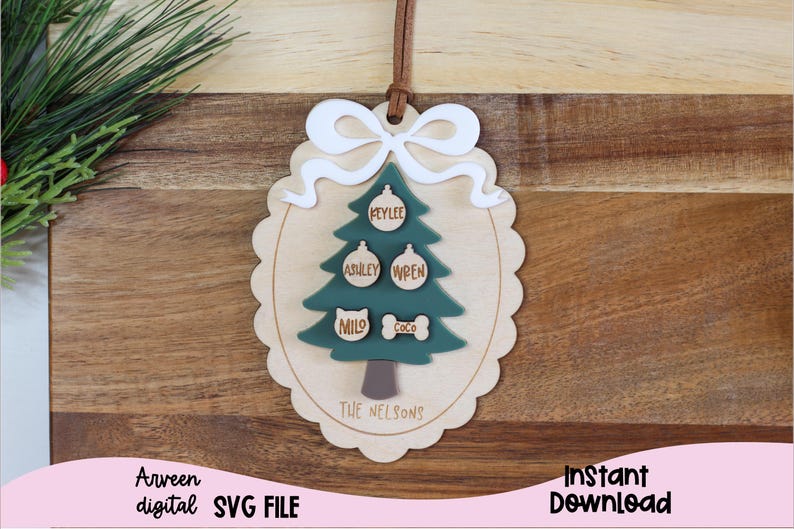 May include: A wooden Christmas tree ornament with a white bow and the names "Klylee", "Ashley", "Wren", "Milo", and "Coco" on the ornaments. The text "The Nelsons" is at the bottom of the ornament.