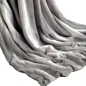 Peut inclure: Une couverture en fausse fourrure douce et moelleuse avec un motif rayé gris et blanc. La couverture est parfaite pour ajouter de la chaleur et du confort à n'importe quelle pièce.