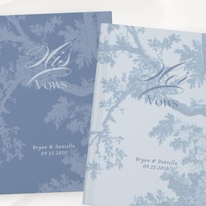 May include: Two wedding vow books with a light blue tree branch design. The words "His Vows" are written in elegant script. The names "Bryan & Daniella" and the date "09.25.2010" are printed at the bottom.